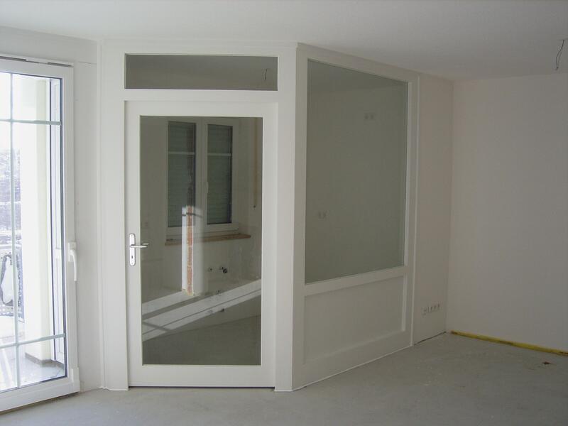 Ein Raum mit einer weißen Tür und einem Fenster, das Tageslicht hereinlässt