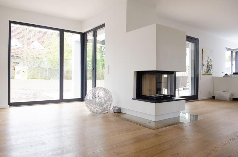 Modernes Wohnzimmer mit einem Kamin und großen Fenstern, die viel Tageslicht hereinlassen