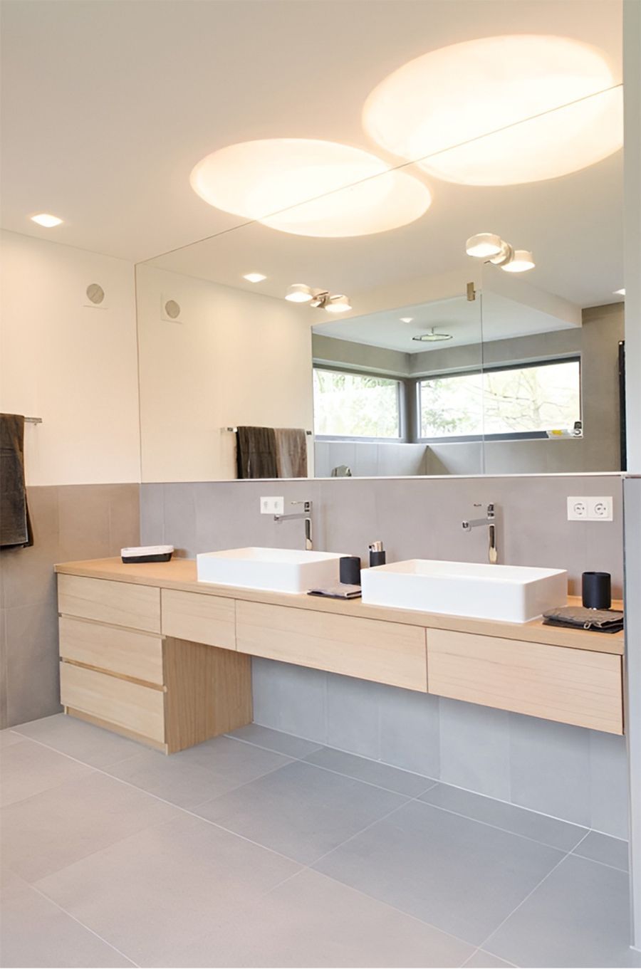 Modernes Badezimmer mit zwei nebeneinanderliegenden Waschbecken und einem Spiegel darüber